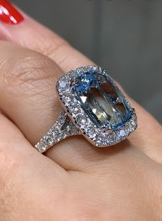 a woman's hand holding an engagement ring with a large blue and white diamond