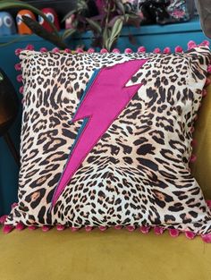 a leopard print pillow with a pink lightning bolt on the front and back, sitting on a yellow chair