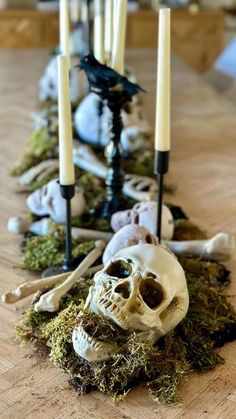 a table topped with candles and skulls on top of moss covered floor next to other items