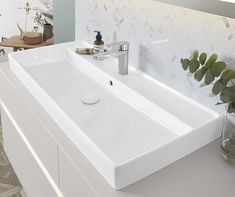 a white bathroom sink sitting on top of a counter next to a vase filled with flowers