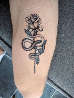 a rose and snake tattoo on the left leg, it is black and white with grey ink