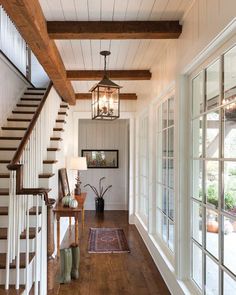 a hallway with wood floors, white walls and wooden railings that lead up to the second floor