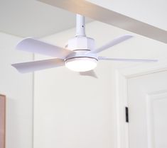 a white ceiling fan in a room with a light on it's side and an open door behind it