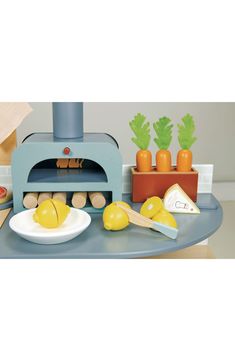 a toy oven sitting on top of a table next to some vegetables and other items