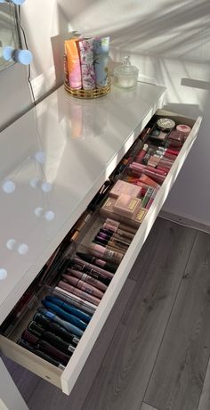 an open drawer on the side of a counter with cosmetics and makeup products in it