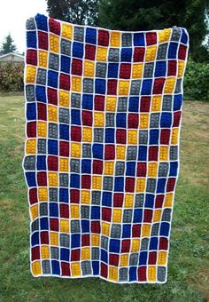 a crocheted blanket is hanging on a clothes line in the grass with trees in the background