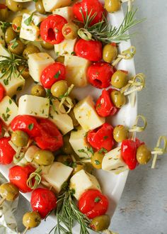 a platter filled with olives, cheese and other vegetables on skewers