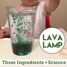 a young boy sitting at a table in front of a cup filled with green liquid