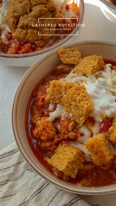 two bowls filled with food sitting on top of a white table covered in cloths