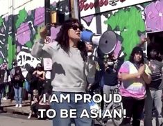 a woman holding a megaphone in front of a group of people on the street