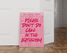 a pink sign that says please don't do cake in the bathroom on a wooden floor