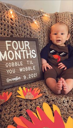 a baby is sitting on a couch next to a sign that says four months gobble til you wobble