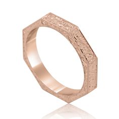 a rose gold wedding ring with intricate engraving on the sides and an engraved design in the middle