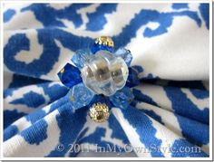 a blue and white patterned fabric with gold accents on the center is featured in this close up photo