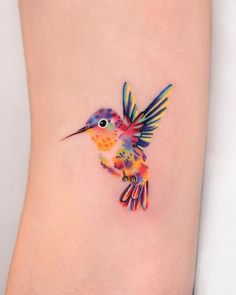 a small colorful bird tattoo on the ankle