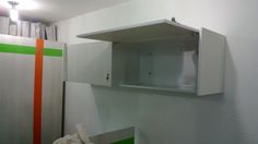 an empty kitchen with white cupboards and green stripes on the wall next to it