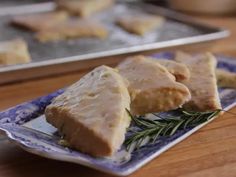 some food is sitting on a blue and white plate with rosemary sprig next to it