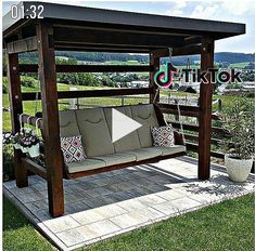 a wooden bench sitting on top of a grass covered field next to a swing chair