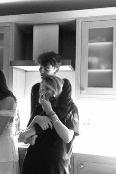 black and white photograph of two women in the kitchen with one woman on her head