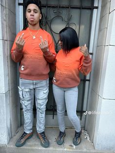 two people standing in front of a door with their hands up and one person wearing an orange shirt