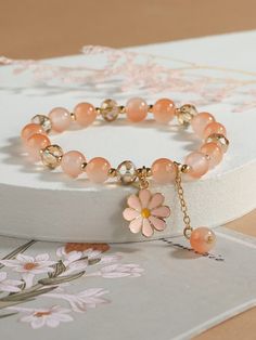 a bracelet with flowers on it sitting on top of a card board next to a box