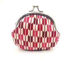 a small red and white purse on a white background with the clasp open to reveal it's contents