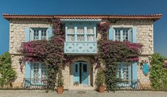 an old stone house with blue shutters and flowers