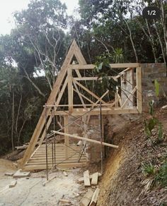 a house being built on the side of a hill with trees in the back ground