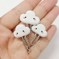 three little white clouds with pink noses are on a person's hand and they are being held in the palm