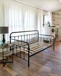 a metal bed frame sitting on top of a hard wood floor next to a window