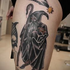 a man with a wizard hat and wand tattoo on his leg