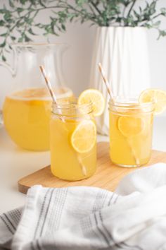 two mason jars filled with lemonade on a cutting board