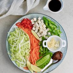 a plate filled with vegetables and sauces next to a cup of coffee on a table