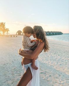 a woman holding a child on the beach