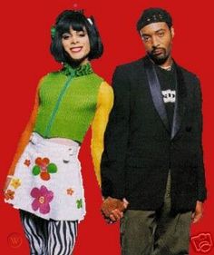 two people standing next to each other in front of a red background with flowers on it