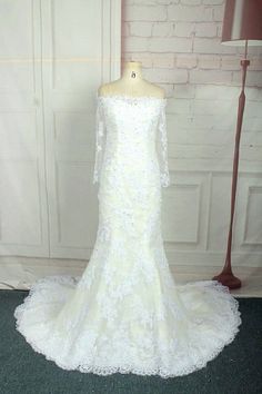 a white wedding dress on display in front of a brick wall