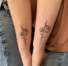 two people with matching tattoos on their arms holding each other's hands and one has a flower tattoo on her left arm