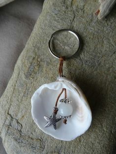 a white shell with a starfish on it is sitting on a rock and has a key chain attached to it