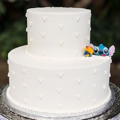 a three tiered white cake decorated with lillies and an elephant figurine