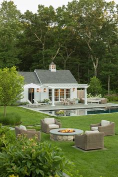 an outdoor living area with chairs, tables and fire pit in front of a pool