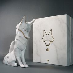 a white dog statue next to a box with the word fox on it's side