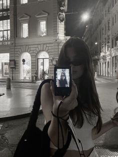 a woman taking a selfie with her cell phone in the city at night time