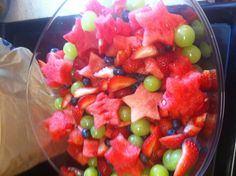 a glass bowl filled with watermelon, grapes and strawberries