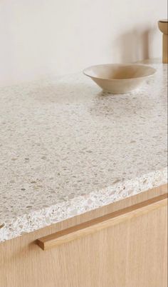 a white bowl sitting on top of a counter next to a wooden drawer and cabinet