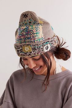 a woman wearing a knitted hat and looking at her cell phone while she smiles