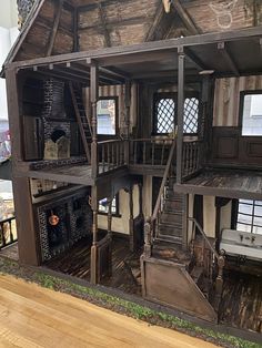 a doll house with stairs to the second floor and windows on both sides, in front of a fireplace