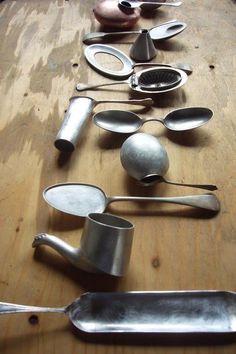 there are many spoons lined up on the wooden table and one is made out of metal