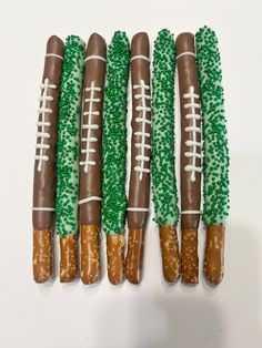 four football shaped pretzels with green and white sprinkles on them