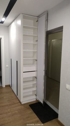 an empty room with white shelving and wooden floors