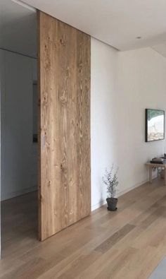 a living room with wood floors and white walls is seen from the hallway to the dining area